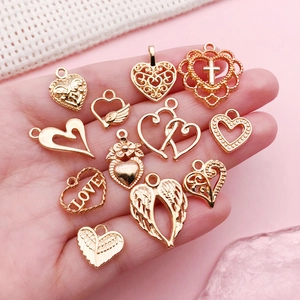 Assorted gold alloy heart and wing charms for DIY jewelry making shown in hand
