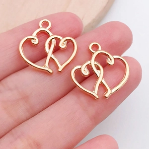Detail of two interlocking golden heart charms for DIY jewelry making held in hand