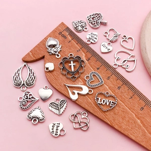 Dettaglio flat lay di ciondoli a cuore e ali in argento antico per gioielli fai-da-te