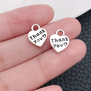 Dettaglio ravvicinato di ciondoli a cuore argento antico con incisione Thank You