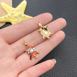 Close-up of golden turtle charms with colorful enamel details held in hand