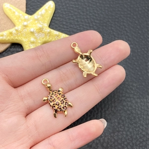 Detailed view of turtle charms with leopard print enamel and polished gold back