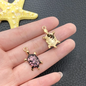 Detailed close-up of pink floral turtle charm with colorful enamel oil drop craft