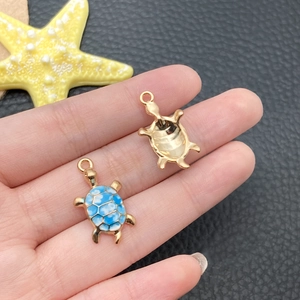 Detailed view of turtle pendant with blue enamel oil drip and gold metal base
