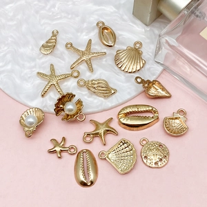Pendentifs dorés thème océan coquillage et étoile de mer pour bijoux DIY sur plateau blanc