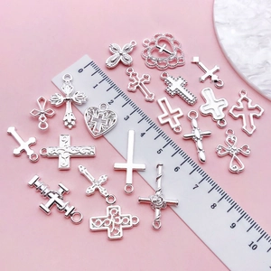 Detailed view of assorted silver alloy cross pendants with scale ruler for size reference