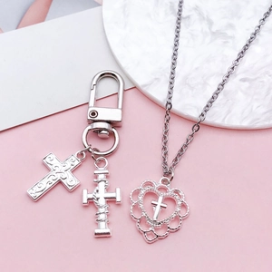 Close-up of bright silver alloy cross pendants with hollow heart design for DIY jewelry