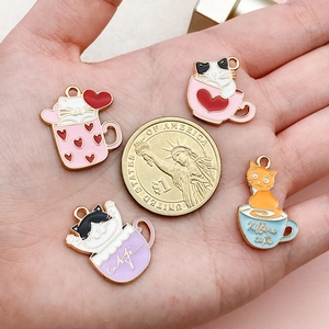 Detailed size reference of cartoon cat tea cup enamel pendants with a coin for scale