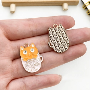 Close-up of cat in a teacup enamel charm pendant showing the gold textured back side