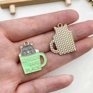 Detailed macro view of enamel cat coffee cup charms with golden mesh back for DIY jewelry