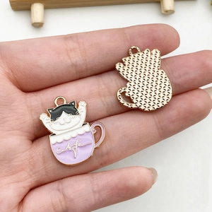 Detail of cartoon cat teacup charms showing colorful enamel finish and gold mesh back