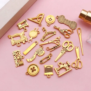 Golden sewing charms set featuring scissors and machine on pink background