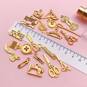 Macro shot of gold sewing themed pendants like vintage machines and scissors for DIY crafts