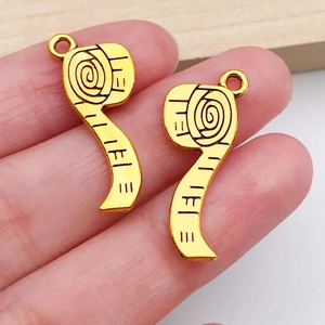 Detail of vintage gold tape measure charms for DIY jewelry making held in hand