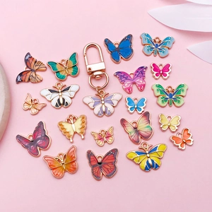 Detalle de colgantes de mariposa coloridos en aleación con bordes dorados sobre fondo rosa