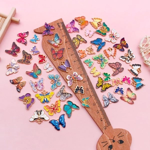 Dijes de mariposa coloridos en fondo rosa con regla de madera para referencia de tamaño
