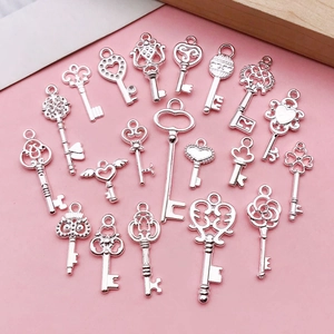 Silver vintage wing heart key pendants for DIY necklaces on a pink background