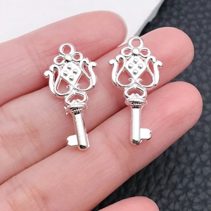 Close-up of silver wing heart key pendants with intricate hollow filigree details