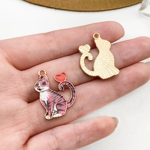 Dettagli fronte e retro del ciondolo a forma di gatto rosa con cuore e base dorata