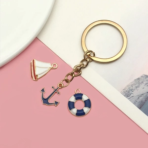 Nautical keychain with gold ring, red sailboat, navy anchor and blue lifebuoy enamel charms