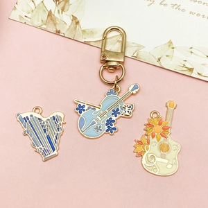 Enamel musical instrument pendants including violin, harp, and guitar with gold keychain