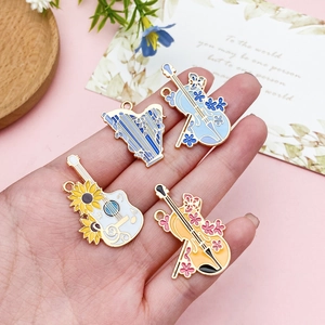 Handheld set of four colorful musical instrument pendants with floral enamel patterns