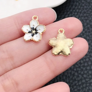 Detail of white flower pendant with black core and gold-plated textured metal back