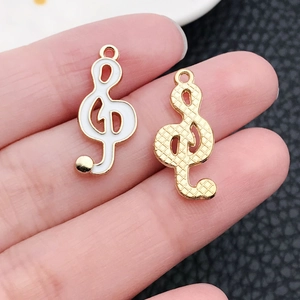 Detailed view of G-clef pendant with white enamel inlay and gold textured finish
