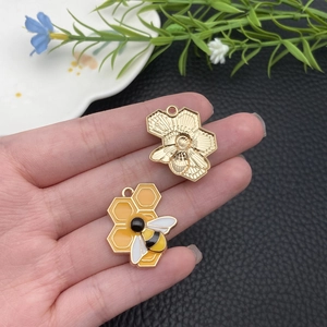 Vue macro des pendentifs abeille et nid d'abeille montrant l'émail jaune et la texture dorée