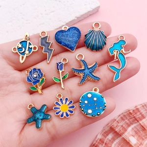 Set di ciondoli smaltati blu a tema oceano e stelle per gioielli fai da te mostrati sulla mano