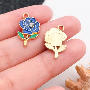 Dettaglio macro di ciondoli a rosa in smalto blu con retro dorato e strass centrale