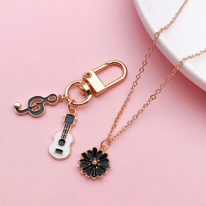 Detail of alloy music keychain with gold treble clef and white guitar oil-drop pendants