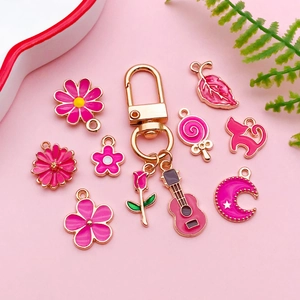 Set met roze emaille hangers en gouden sleutelhangers met bloemen en diverse cartoonvormen