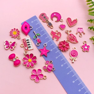Set van roze emaille bedeltjes met creatieve bloem- en hartvormen getoond met liniaal