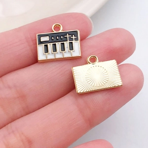 Detail of piano keyboard enamel pendant with gold metal sunburst texture backing