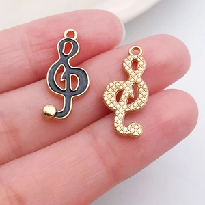 Detail of G-clef musical note charms in black enamel and gold mesh finish for DIY jewelry