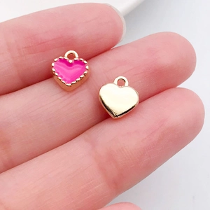 Macro-opname van twee hartvormige DIY-hangers in roze emaille en gepolijste goudlaag