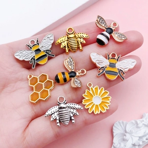 Detailed set of bee, honeycomb and sunflower alloy charms held in hand for DIY jewelry