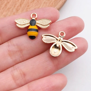 Macro detail of enamel bee charms for DIY jewelry making with gold-plated finish