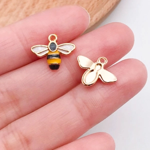 Macro detail of bee pendant charm showing yellow enamel work and golden metal back