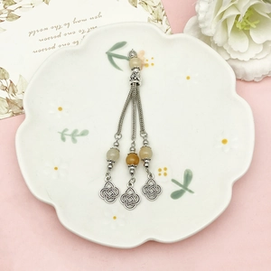 Orecchini etnici con nappe argentate e nodi celtici su un piatto in ceramica a fiori