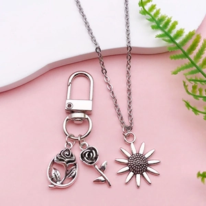 Detail view of sunflower necklace and double rose keychain in vintage silver finish
