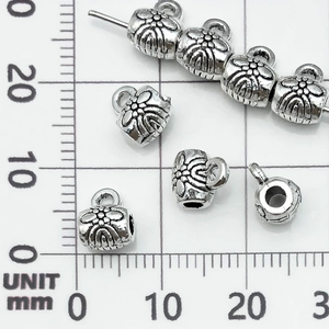 Dettaglio macro di perline distanziatrici a girasole in argento antico per gioielli DIY