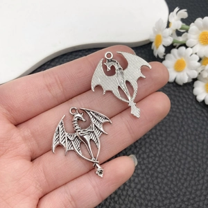 Vue détaillée d'un pendentif dragon en argent vieilli tenu à la main pour la taille