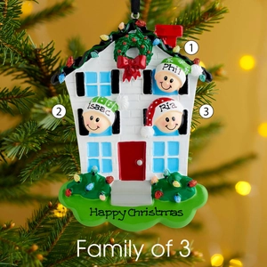 Detailed view of personalized resin family house ornament hanging on a Christmas tree