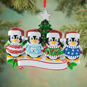 Close-up of four cute penguin family Christmas tree ornaments with a white DIY banner