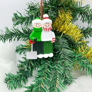 Detail of hand-painted resin Christmas couple pendant hanging on a festive decorated tree
