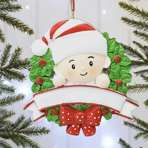 Détail macro d'un ornement de bébé en résine avec bannière blanche et nœud de Noël