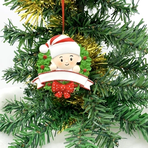 Détail de l'ornement bébé de Noël dans une couronne de houx avec bannière blanche