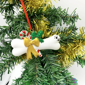 Detailed resin dog bone Christmas ornament with gold bow and candy cane on tree